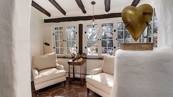 A cozy room with two beige armchairs, a wooden table, and a patterned rug.