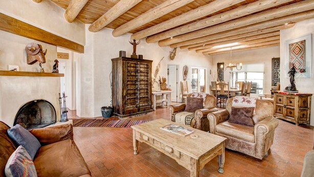 A rustic living room with exposed wooden beams, a fireplace, leather sofas, and a traditional cabinet. - Moonstar | Pet Friendly, Rooftop Deck, 360 Views! (Santa Fe)