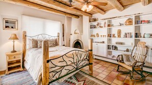 A cozy bedroom with a wooden bed, a fireplace, a bookshelf, and a rocking chair. - Moonstar | Pet Friendly, Rooftop Deck, 360 Views! (Santa Fe)