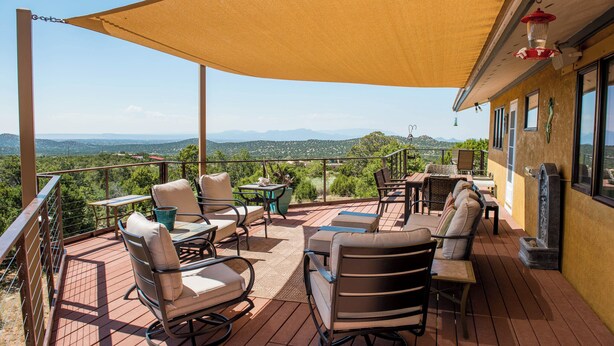 A covered outdoor patio with seating, a table, and a view of the landscape. - Sunset Haven | Mountain Views, Shuffleboard! (Santa Fe)