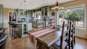 A spacious kitchen with a central island, bar stools, and a dining table with chairs. - Sunset Haven | Mountain Views, Shuffleboard! (Santa Fe)