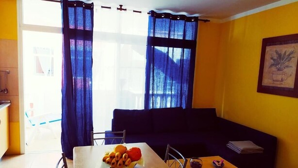 Een woonkamer met een eettafel, een bank en een raam met gordijnen.