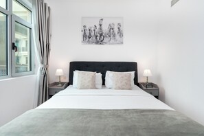 A neatly made bed with a grey blanket, two bedside lamps, and a wall-mounted picture of horses. - Lux BnB I Turia Tower I Lake & Garden View (Dubai)