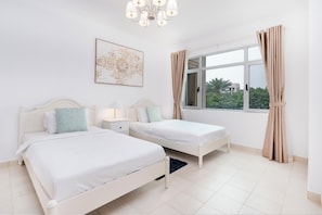 Ein Schlafzimmer mit zwei Betten, einem großen Fenster mit Vorhängen, einer Kristallleuchter und einem Wandbild.