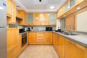 A modern kitchen with wooden cabinets, granite countertops, a stainless steel sink, and a built-in oven.