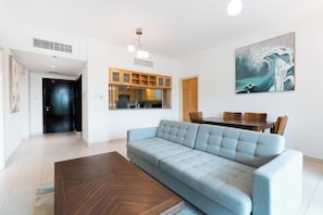 Ein modernes Wohnzimmer mit einem hellblauen Sofa, einem Holzesstisch und einem großen Gemälde einer Welle.