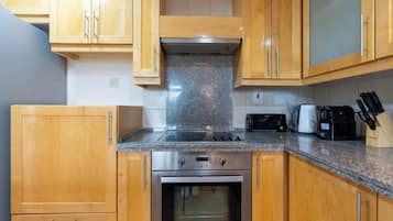 Una cocina con gabinetes de madera, estufa de acero inoxidable, microondas y tostadora.