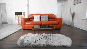 A living room with a leather sofa, a coffee table, and a fur rug. - FRESHLY RENOVATED 2 BR APARTMENT! (Ansonia)