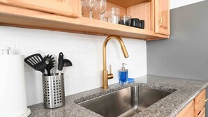 A kitchen with granite countertops, a stainless steel sink, wooden cabinets, and a gold faucet. - FRESHLY RENOVATED 2 BR APARTMENT! (Ansonia)