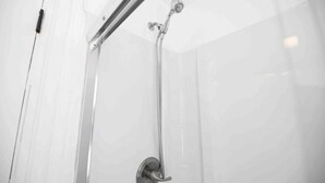 A shower with a handheld showerhead and a wall-mounted faucet. - FRESHLY RENOVATED 2 BR APARTMENT! (Ansonia)
