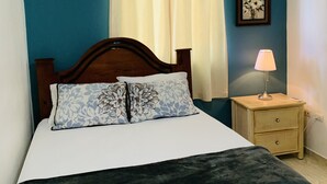 A bedroom with a bed, a nightstand, a lamp, a ceiling fan, and an air conditioning unit. - Villa Apartment in North Coast of Dominican Republic (Cabrera)