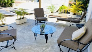 A patio area with a glass table surrounded by cushioned chairs and a sofa. - Villa Apartment in North Coast of Dominican Republic (Cabrera)