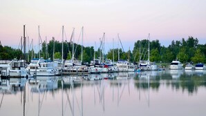 A marina with various boats docked, calm water, and trees in the background. - 4+ acres with 100 feet of sugar sand beach on Lake Huron (Cheboygan)