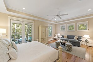 Ein geräumiges Schlafzimmer mit einem großen Bett, einem Deckenventilator und Blick auf einen Balkon mit Pool.