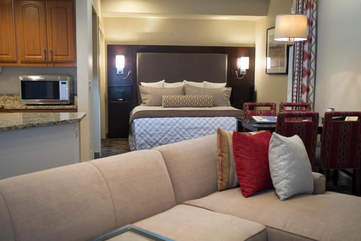 A hotel room with a bed, a sofa, a dining table, and a microwave.