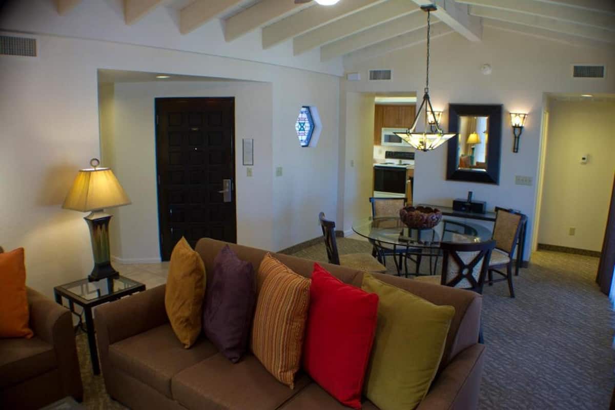 A living room with a sofa, a lamp, and a dining area with a table and chairs.