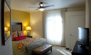 A hotel room with a bed, a television, a ceiling fan, and a window with curtains. - Scottsdale Camelback Resort VRHost (Scottsdale)