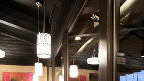 A bar area with a polished granite countertop, black bar stools, and pendant lighting.