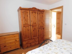 Ein Schlafzimmer mit Holzschrank, Nachttisch und einem Bett mit Blumenmuster.