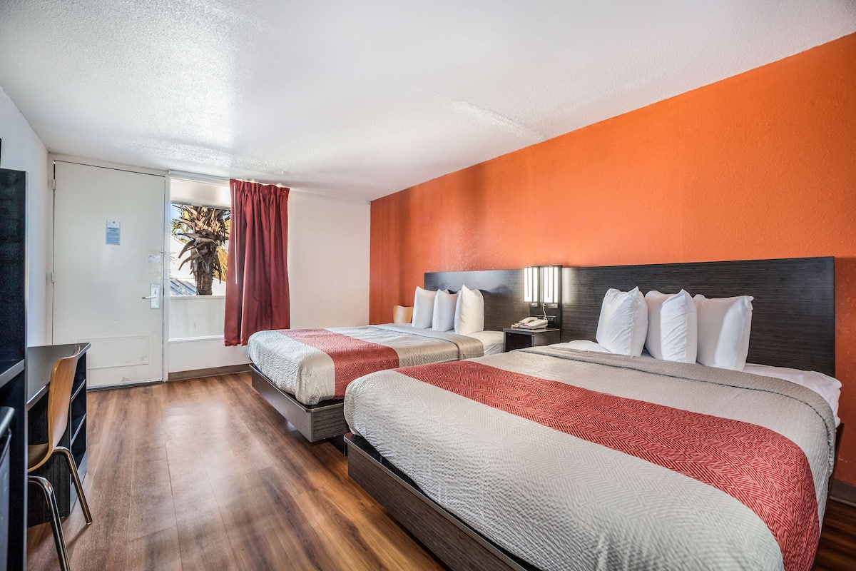 Une chambre d’hôtel avec deux lits, un bureau et une télévision.