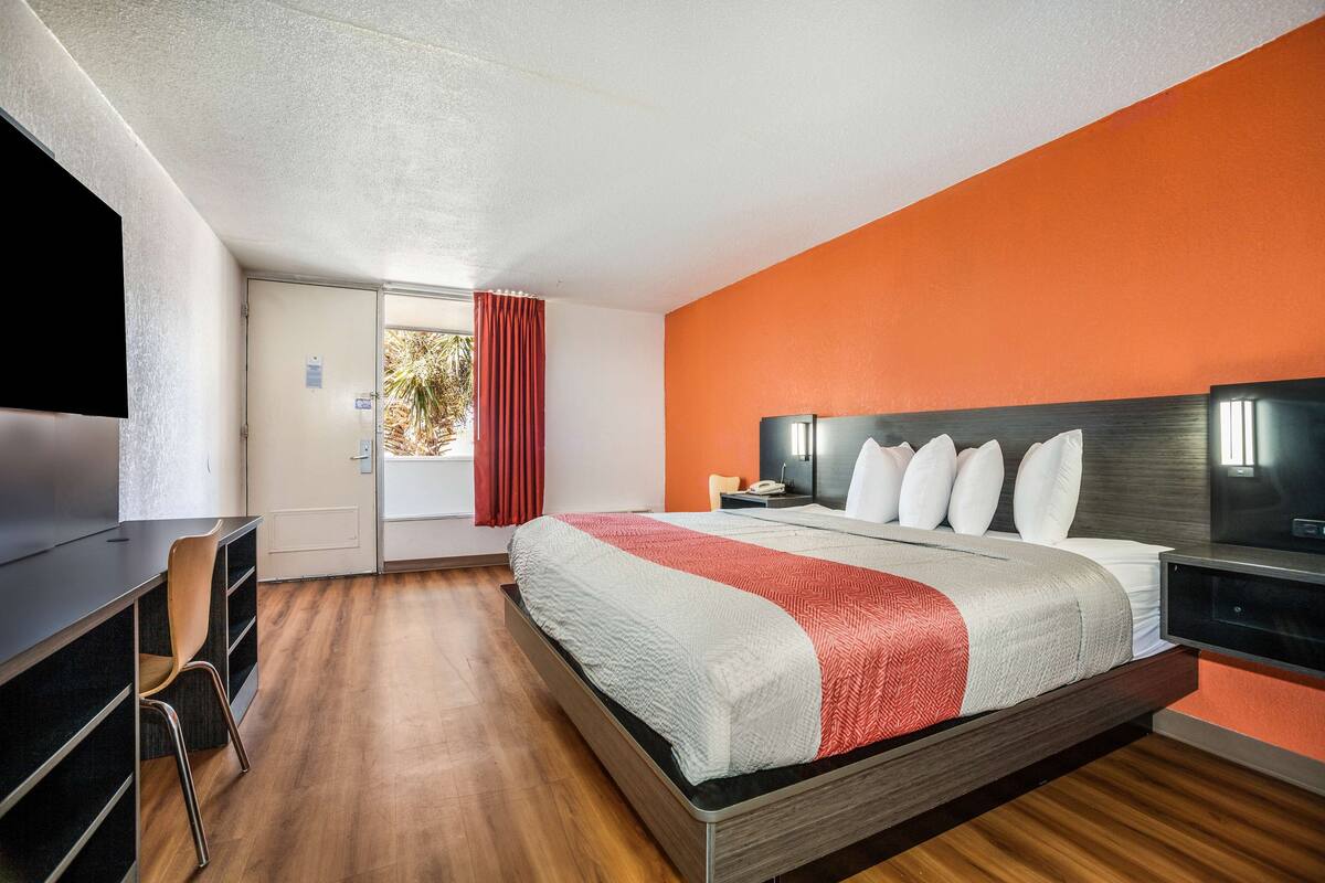 Une chambre d’hôtel moderne équipée d’un lit, d’un bureau et d’une télévision.