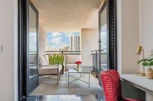 A modern interior with a sofa, a table, and a chair. There is a window with a view of buildings.