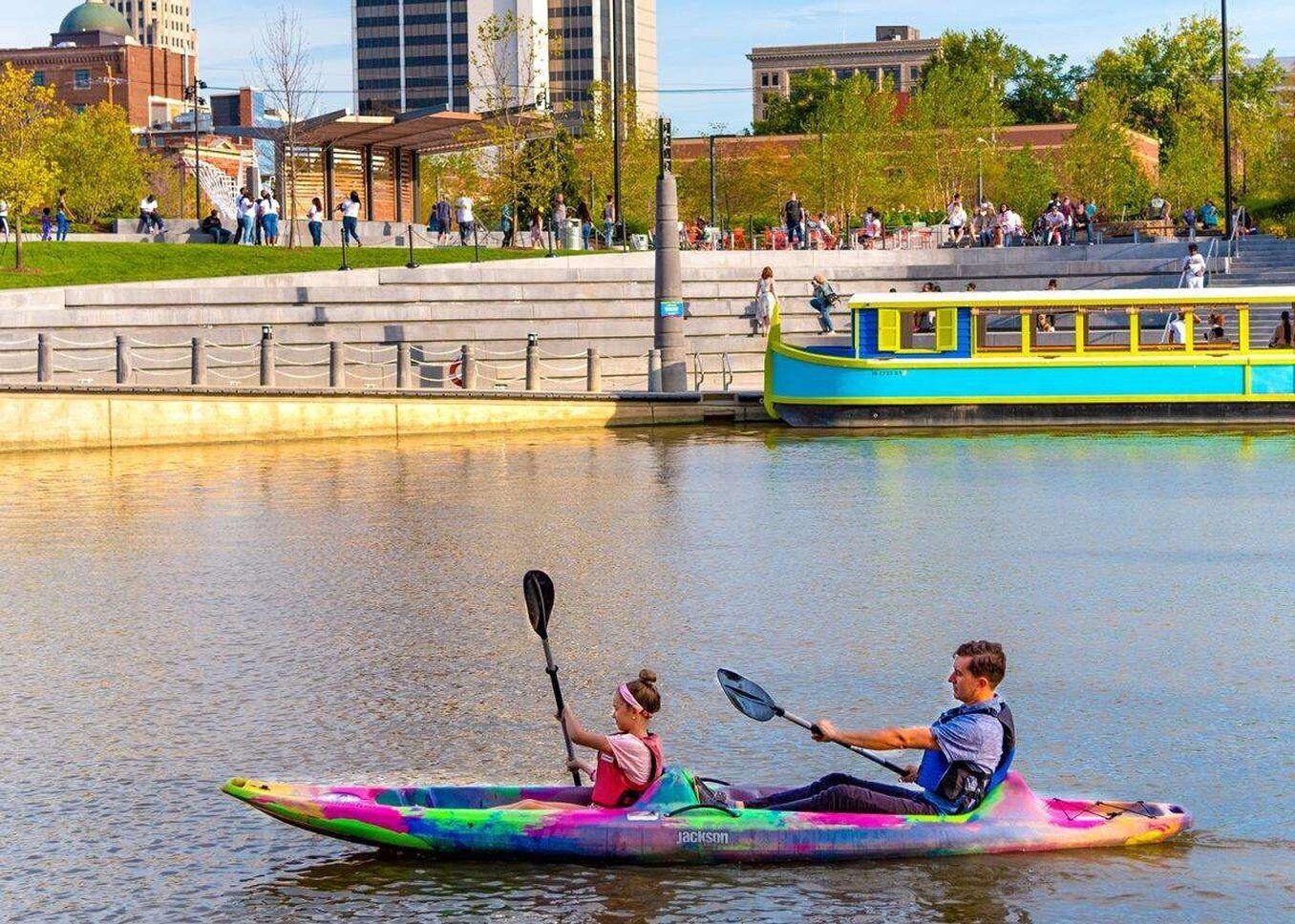 A kayak on a river with a cityscape in the background.