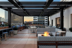 Una terraza en la azotea con mobiliario exterior, una chimenea y vistas del horizonte urbano.