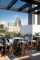 Una terraza con sillones de mimbre y una mesa, con vistas a un paisaje urbano donde destaca un edificio con cúpula.