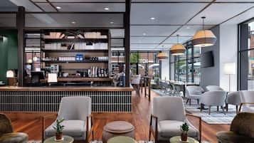 Un espace bar moderne doté d’une bibliothèque, de sièges et offrant une vue sur la rue.