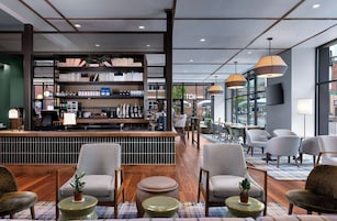 A modern bar area with a bookshelf, seating, and a view of the street.