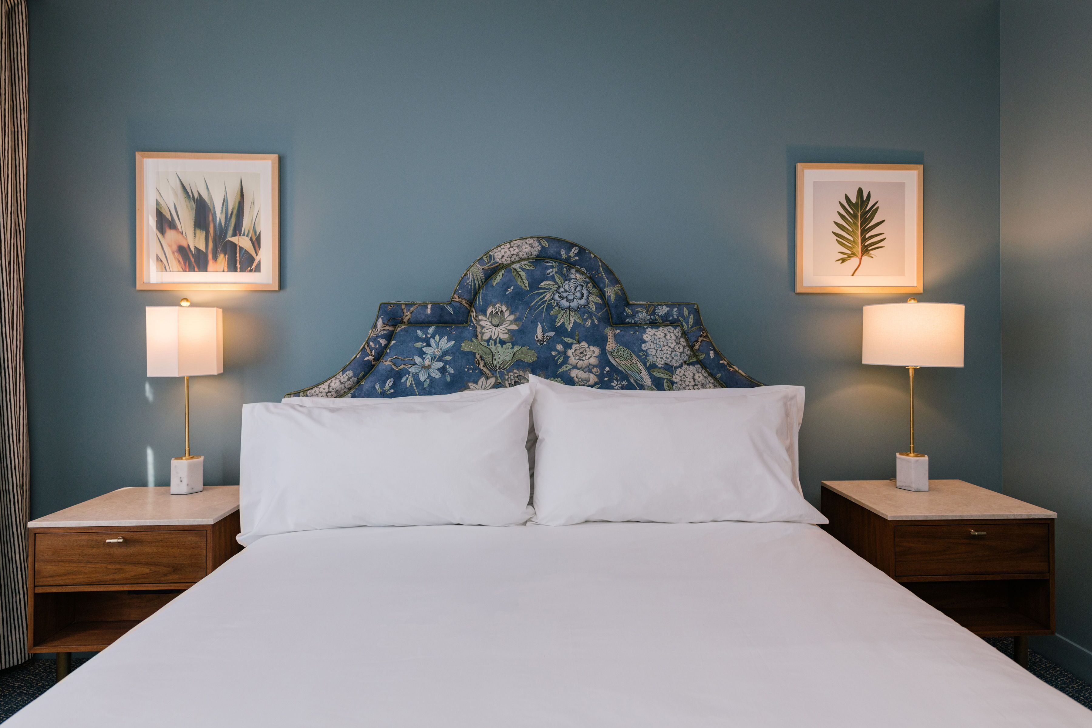 A hotel room with a large bed, two nightstands, and two wall-mounted lamps.