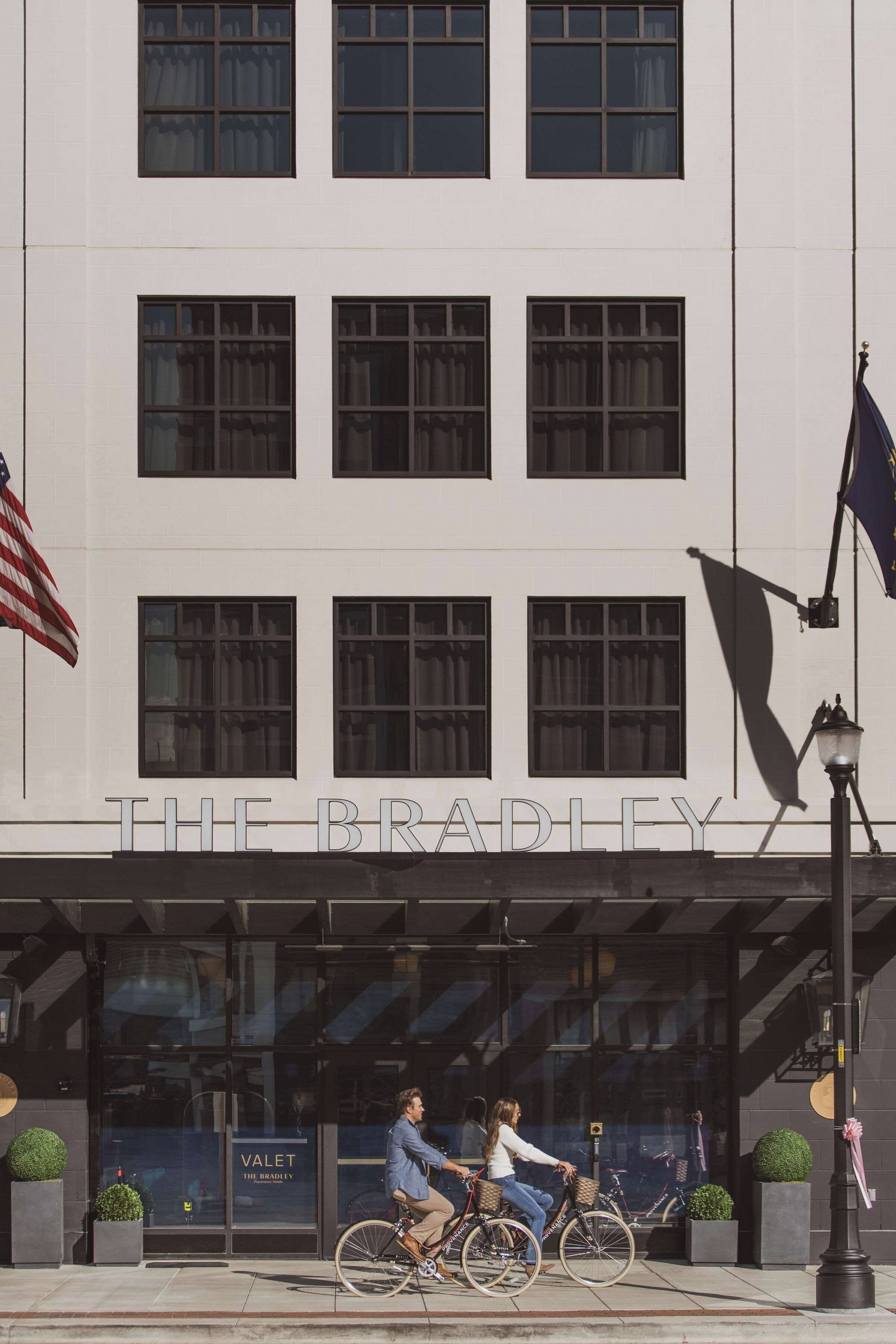 Un edificio con un letrero que dice 'THE BRADLEY' y una tienda con un letrero de 'VALET THE BRADLEY'.
