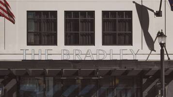 Un edificio con un letrero que dice 'THE BRADLEY' y una tienda con un letrero de 'VALET THE BRADLEY'.