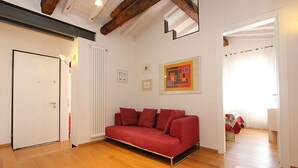 A room with a red sofa, wooden flooring, a white door, and a radiator. - Appartamento con Terrazze (Venezia)
