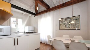 A modern kitchen with white cabinets, a built-in microwave, and a gas stove. There is a dining table with four chairs and a large framed picture on the wall. - Appartamento con Terrazze (Venezia)