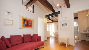 A modern living room with a red sofa, wooden flooring, and artwork on the walls. - Appartamento con Terrazze (Venezia)