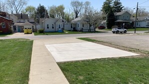 Una calle residencial con casas, aceras y un área verde.
