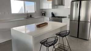 A modern kitchen with a central island, stainless steel appliances, and pendant lighting. - Stylish Palm Springs House with Large Pool (Palm Springs)