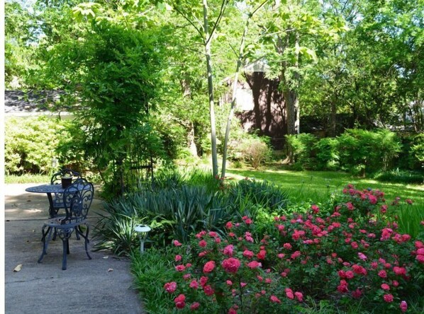 Relax in a serene garden setting surrounded by lush greenery and vibrant flowers, perfect for outdoor dining or unwinding.