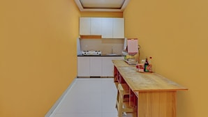 Une cuisine compacte avec des meubles blancs, un plan de travail en bois et un petit coin repas.
