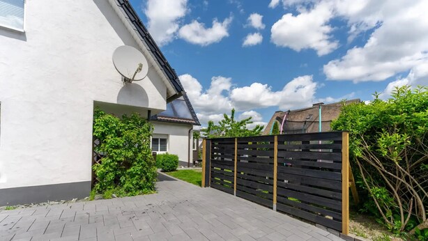 A paved pathway leading to a house with a satellite dish, a wooden fence, and greenery. - Loftstyle Panorama Bödefeld (Schmallenberg)
