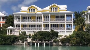 Et flere etagers hotel ved vandet med balkoner, en dock og krystalklart vand.