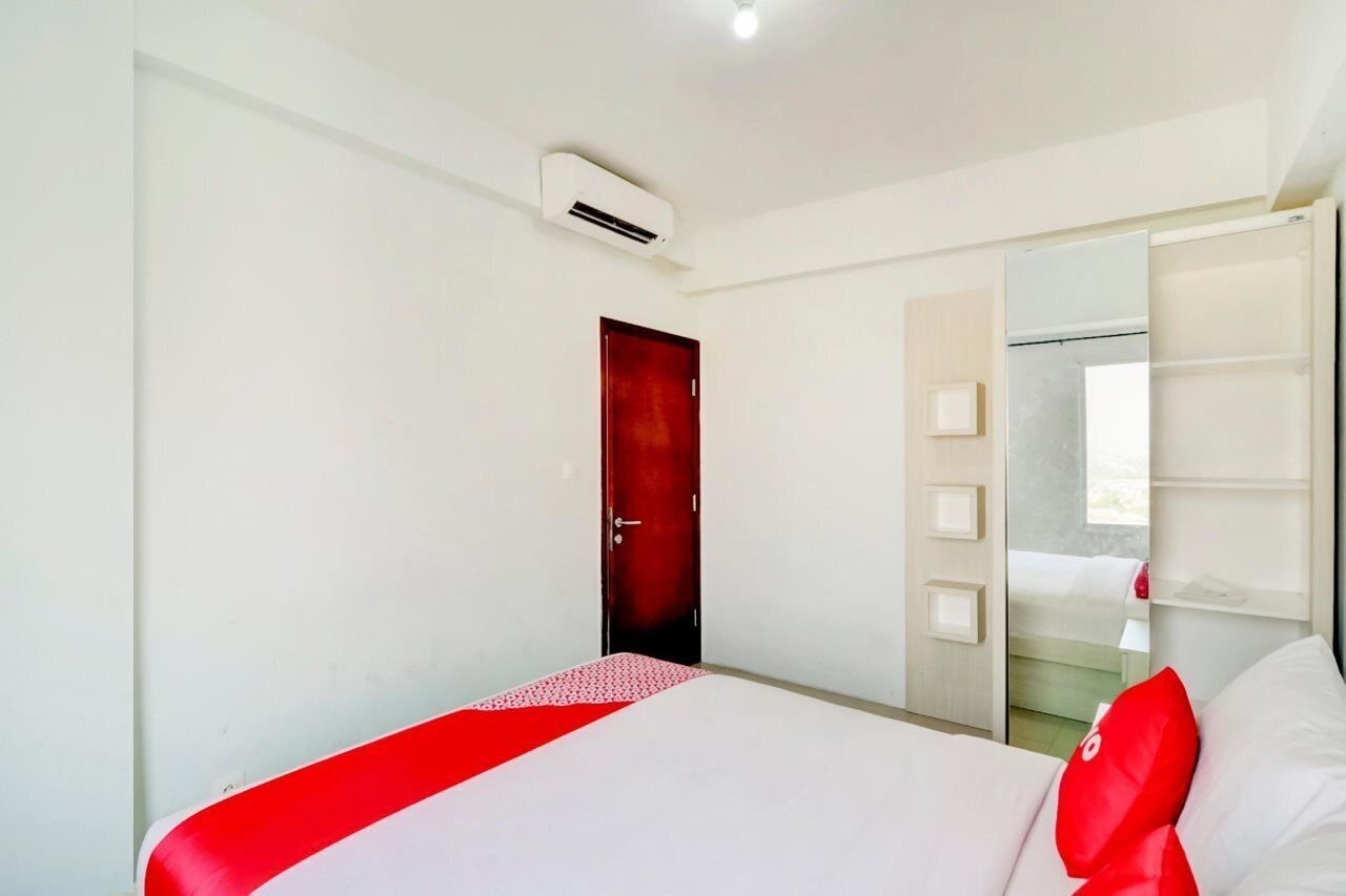 A hotel room with a bed, a wardrobe, a mirror, and an air conditioning unit.