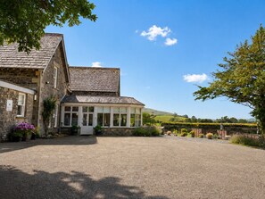 Un bâtiment en pierre doté d’un porche couvert et d’une allée gravillonnée.