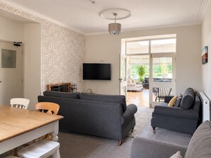 A living room with a sofa, a dining table, and a television.