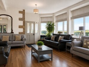 A spacious living room with a fireplace, a large window with a view, and a modern chandelier.