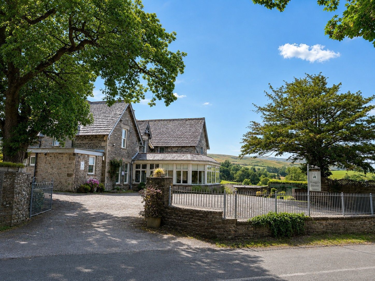 A stone house with a traditional design, a fenced driveway, and a clear view of the surrounding countryside.