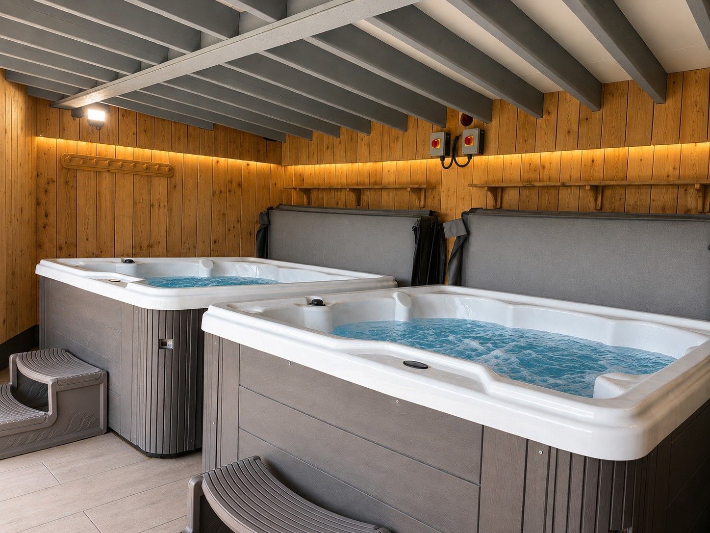A spa area with two hot tubs, wooden walls, and a ceiling with exposed beams.