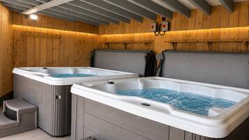 A spa area with two hot tubs, wooden walls, and a ceiling with exposed beams.
